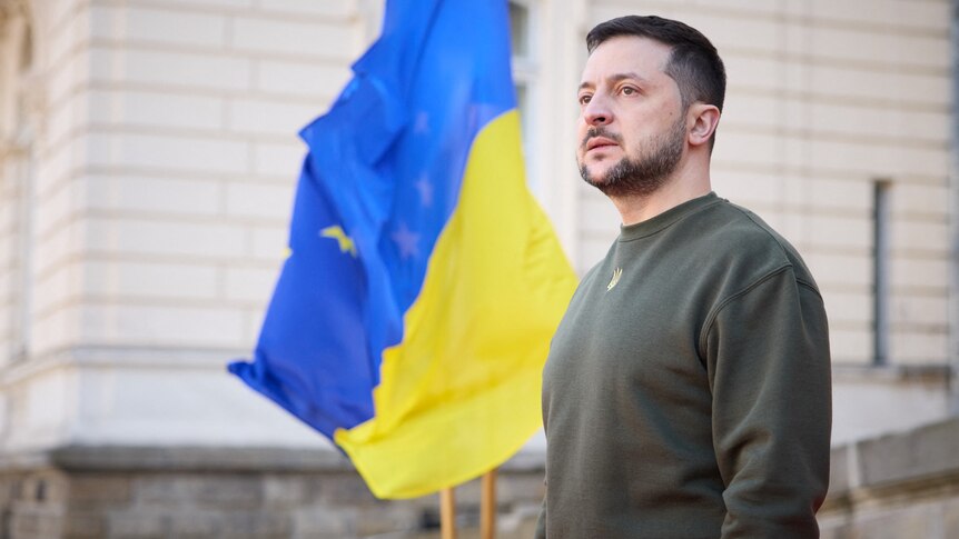 “一名身穿军装的男子站在乌克兰国旗前”